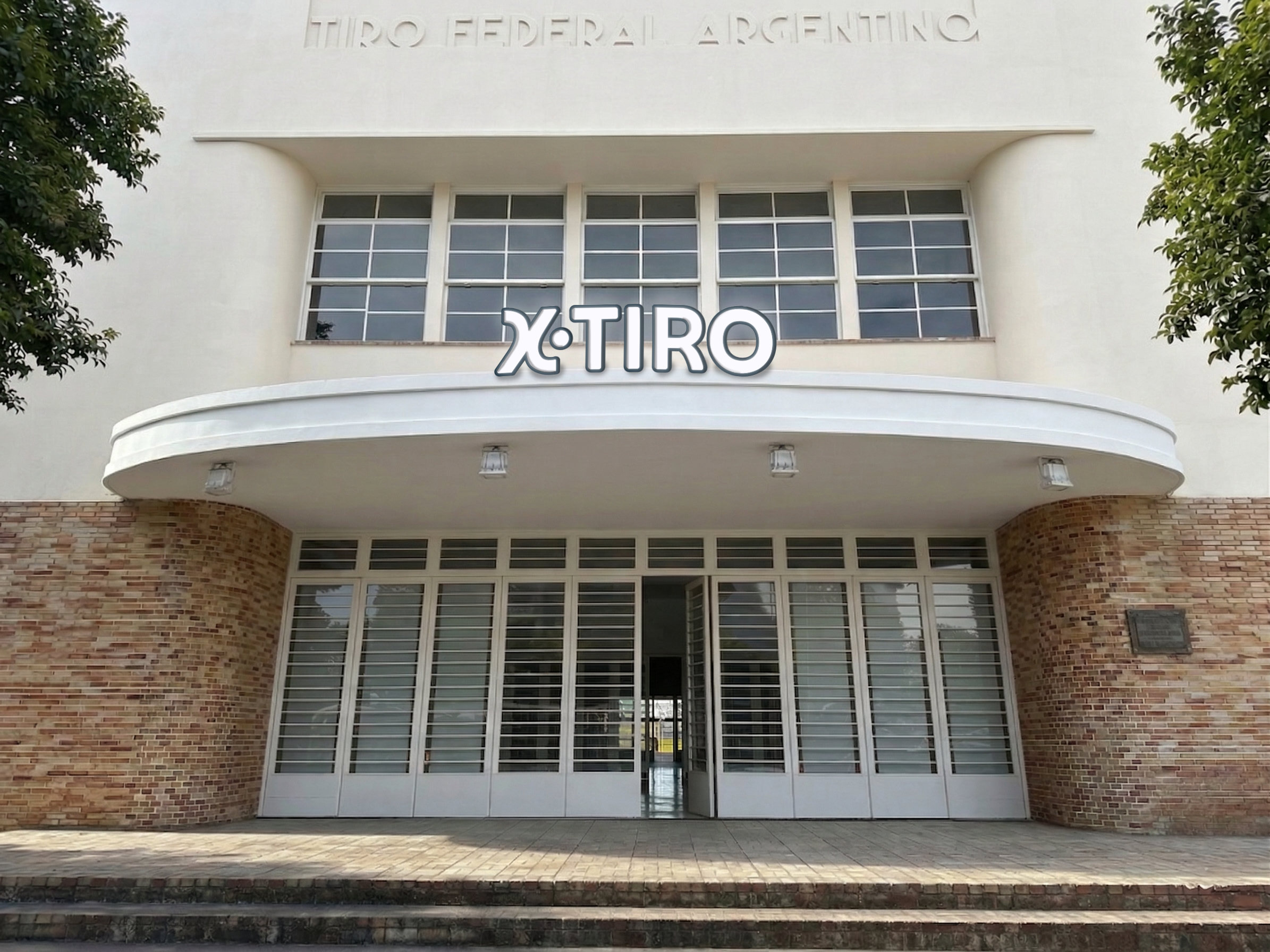 La fachada racionalista restaurada, de día, con el cartel XTiro sobre el acceso.